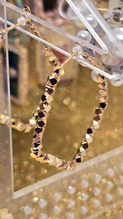 18K Rosegold Ohrringe mit funkelnden Facetten am Acryl-Display