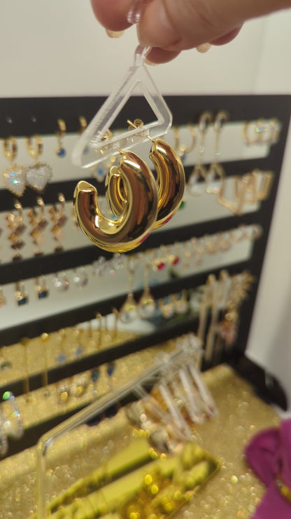 Video: Goldene Creolen aus Edelstahl in der Hand vor dem Schmuckdisplay